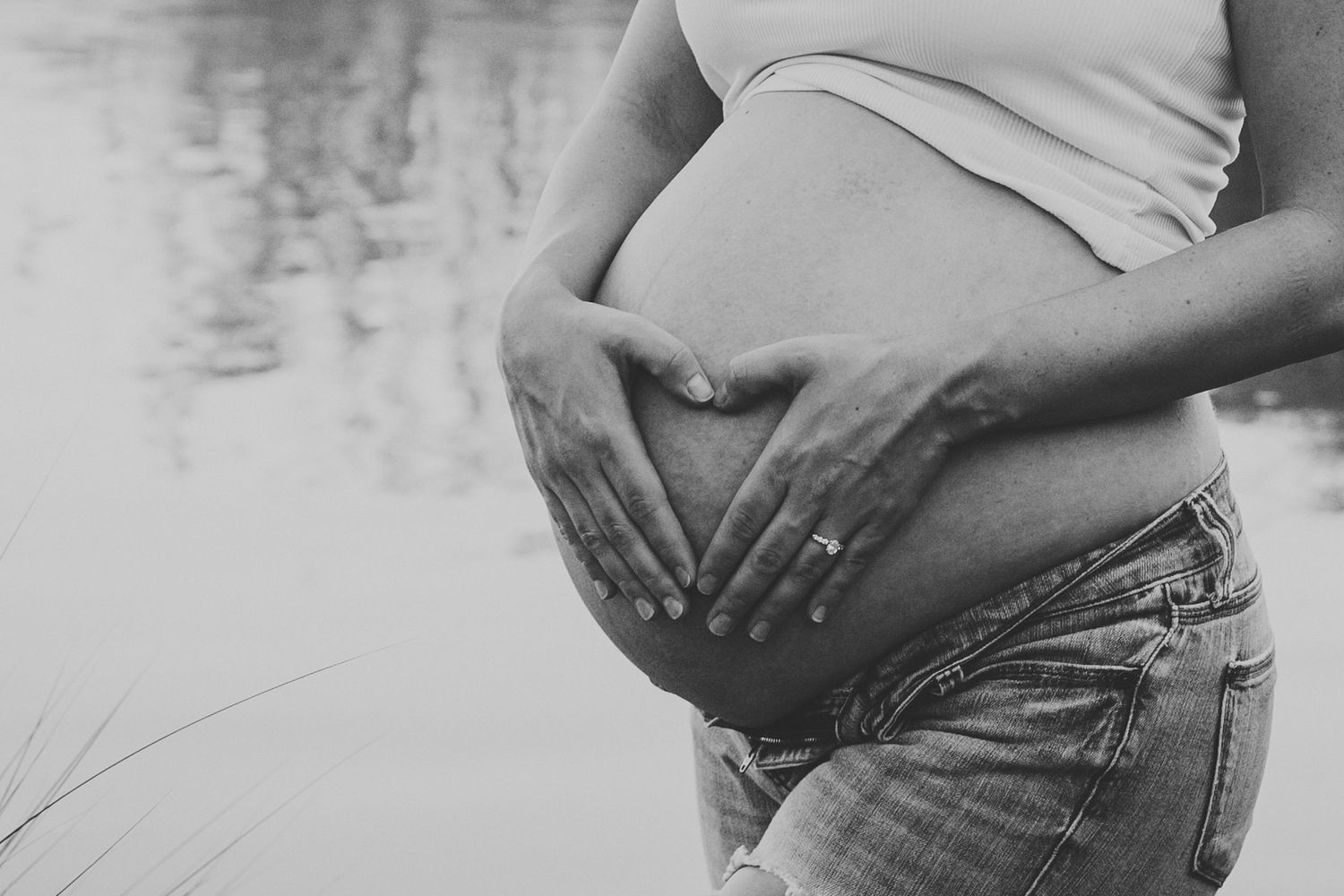 A series of black and white maternity photos showing a pregnant woman's belly in casual clothing.