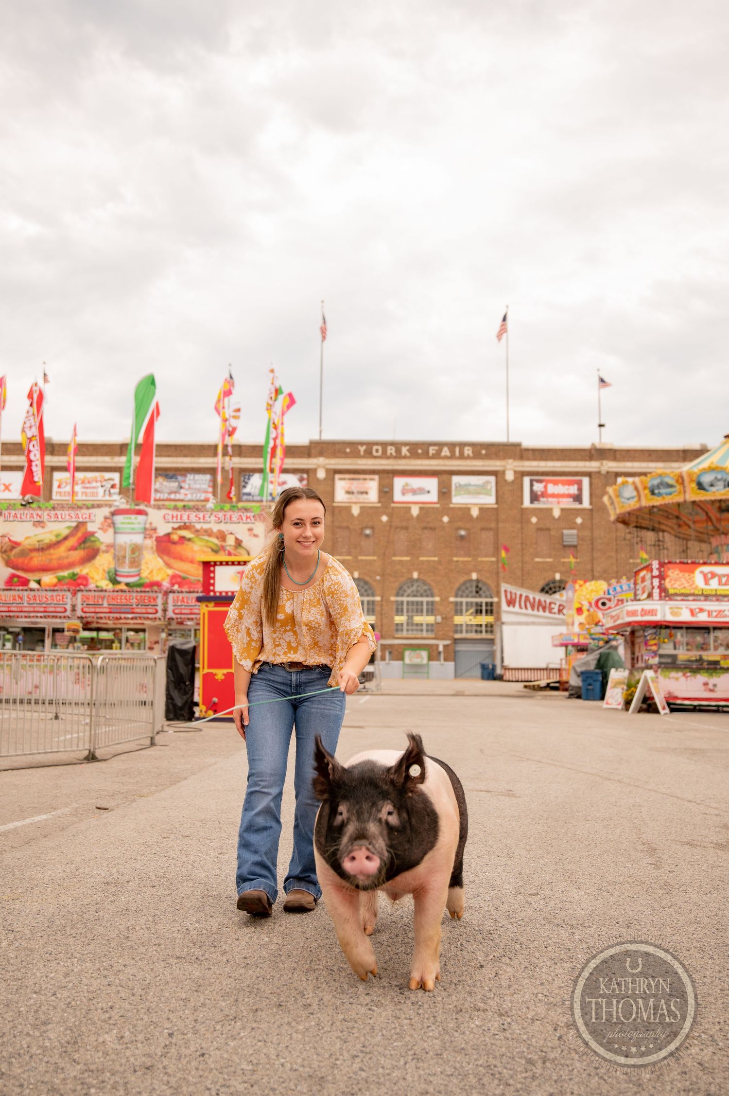 A black and pink show pig stands with its handler at the York Fair entrance.