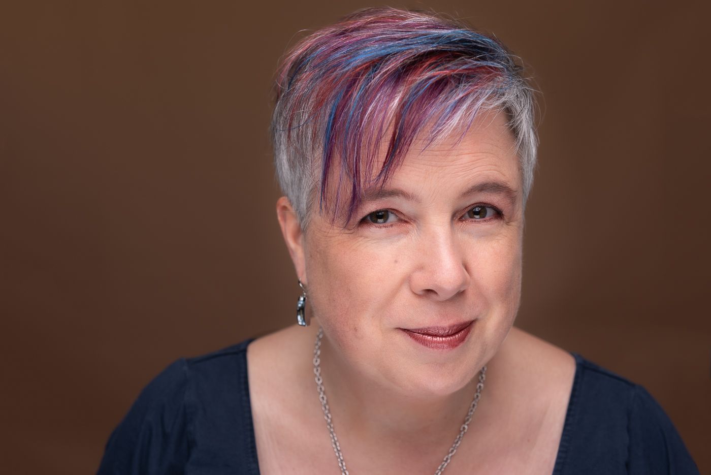 Studio headshot of a woman with colourful hair.