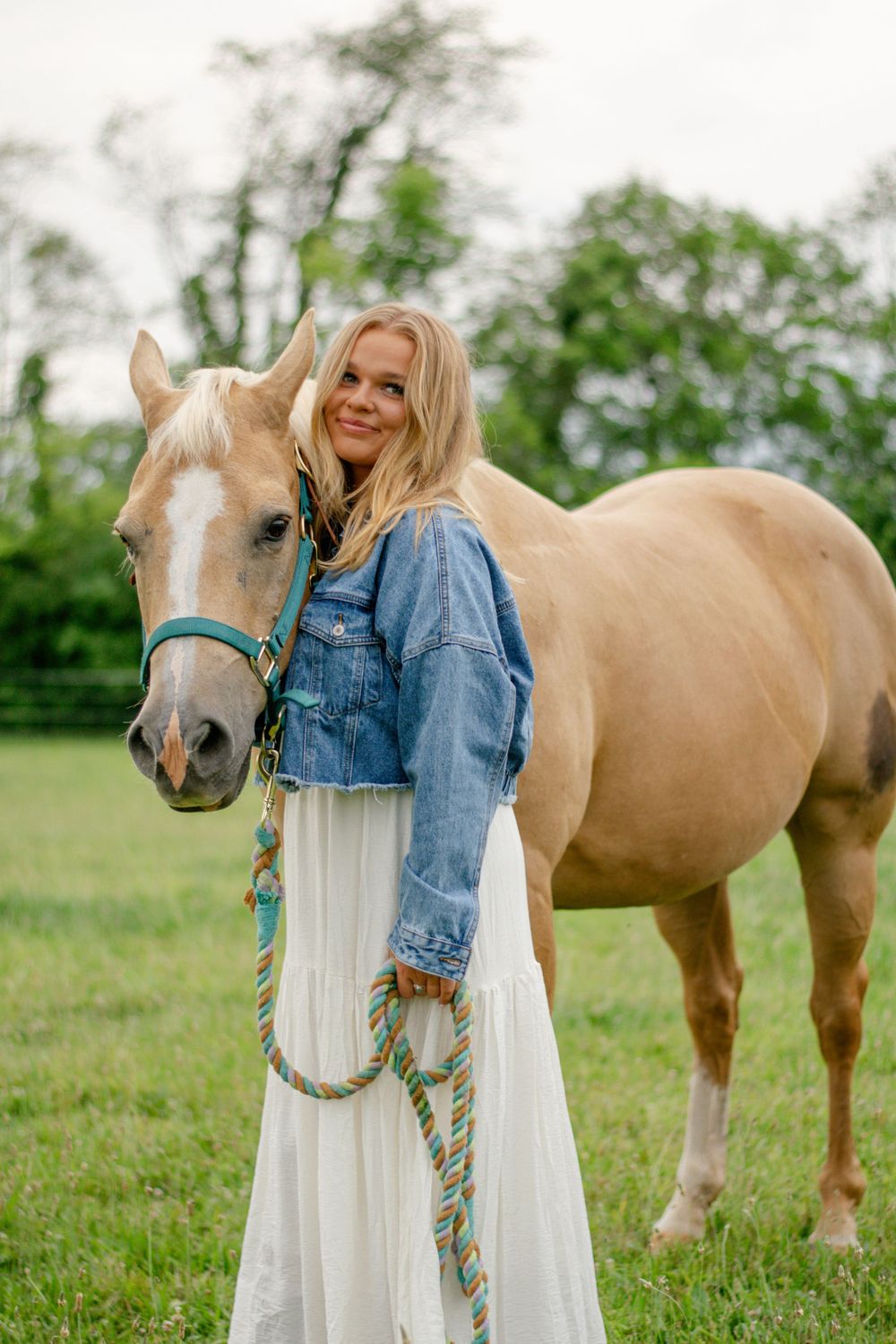 High school senior posing with her horse in a field
