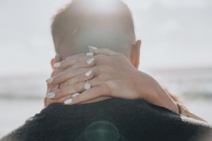 Close-up of hands with a new engagement ring wrapped around in an embrace.