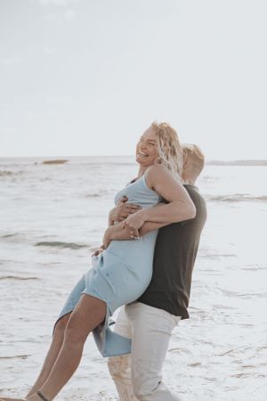 A romantic couple embracing on a sandy beach at sunset.