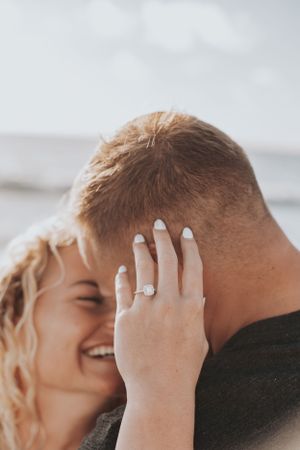 Close-up shot of hands embracing with a sparkling engagement ring visible.