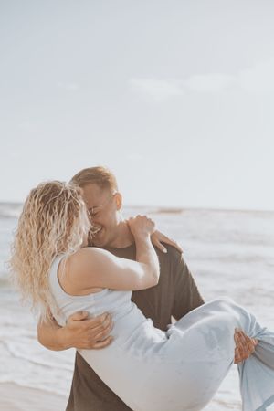 A couple sharing romantic embraces during their beachside engagement photoshoot.