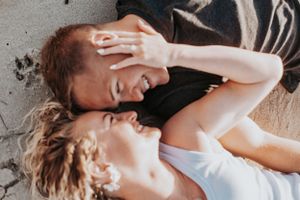 Intimate couple laying together on sandy beach during romantic photoshoot.