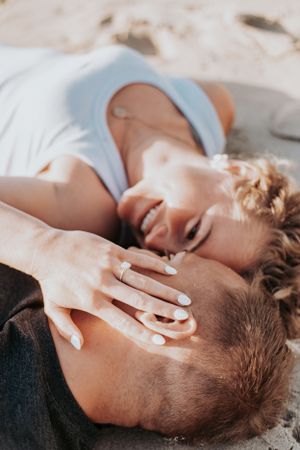 Tender moment between couple embracing on beach with soft lighting.