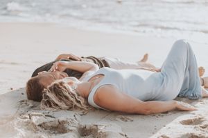 Romantic beach photoshoot with couple lying in the sand.