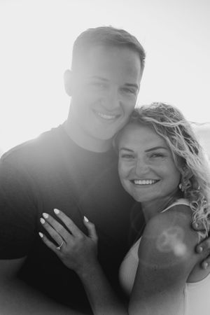 Sunlit portrait of a happy couple showing off an engagement ring.