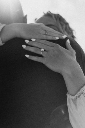 Close-up black and white photo of hands showing off a new engagement ring.