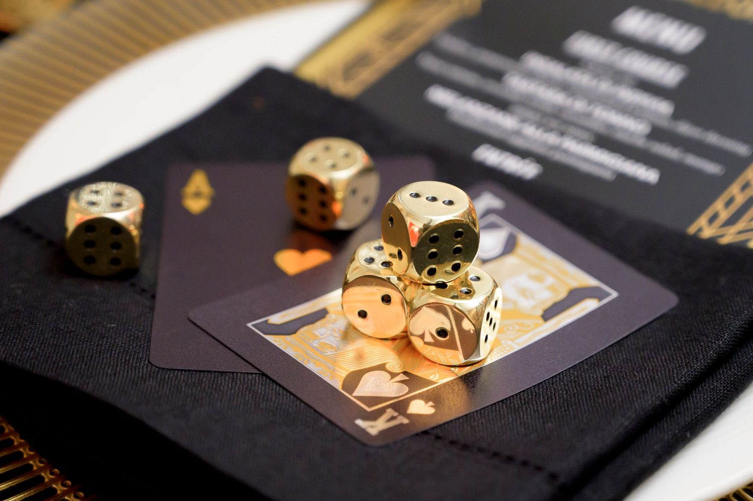 Gold metallic dice scattered on black playing cards create an elegant gaming setup with rich contrast and texture.