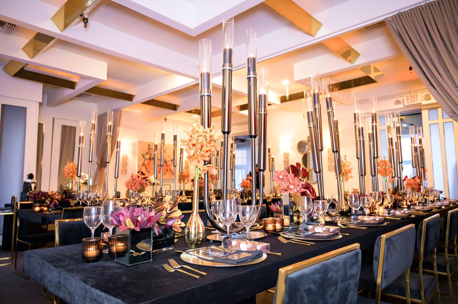 Elegant reception table decorated with tall silver candelabras, black linens, and pink floral arrangements.