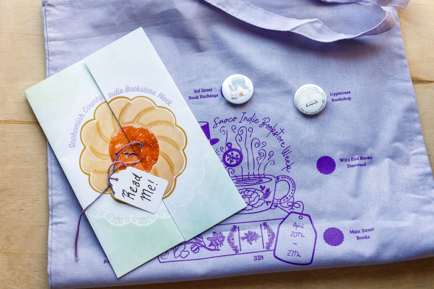 Purple and white merchandise with illustrated design and decorative buttons.