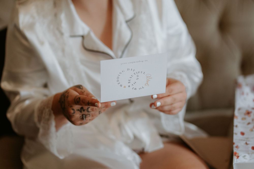 Someone wearing a white shirt holds a delicate white card with embossed details.
