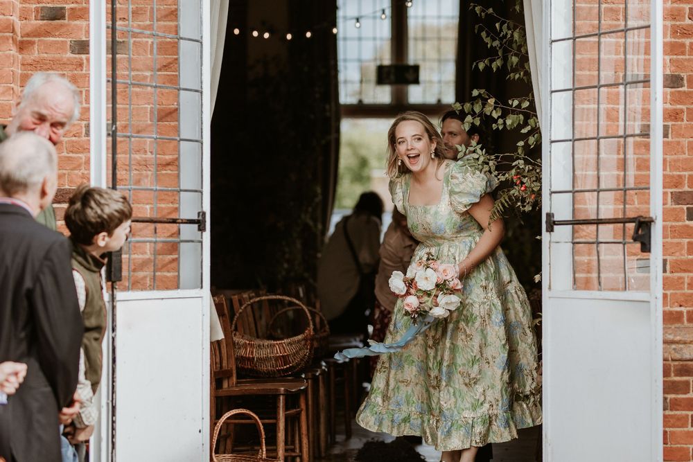 Wedding party gathering in front of a rustic brick wall with string lights creating a warm ambiance.