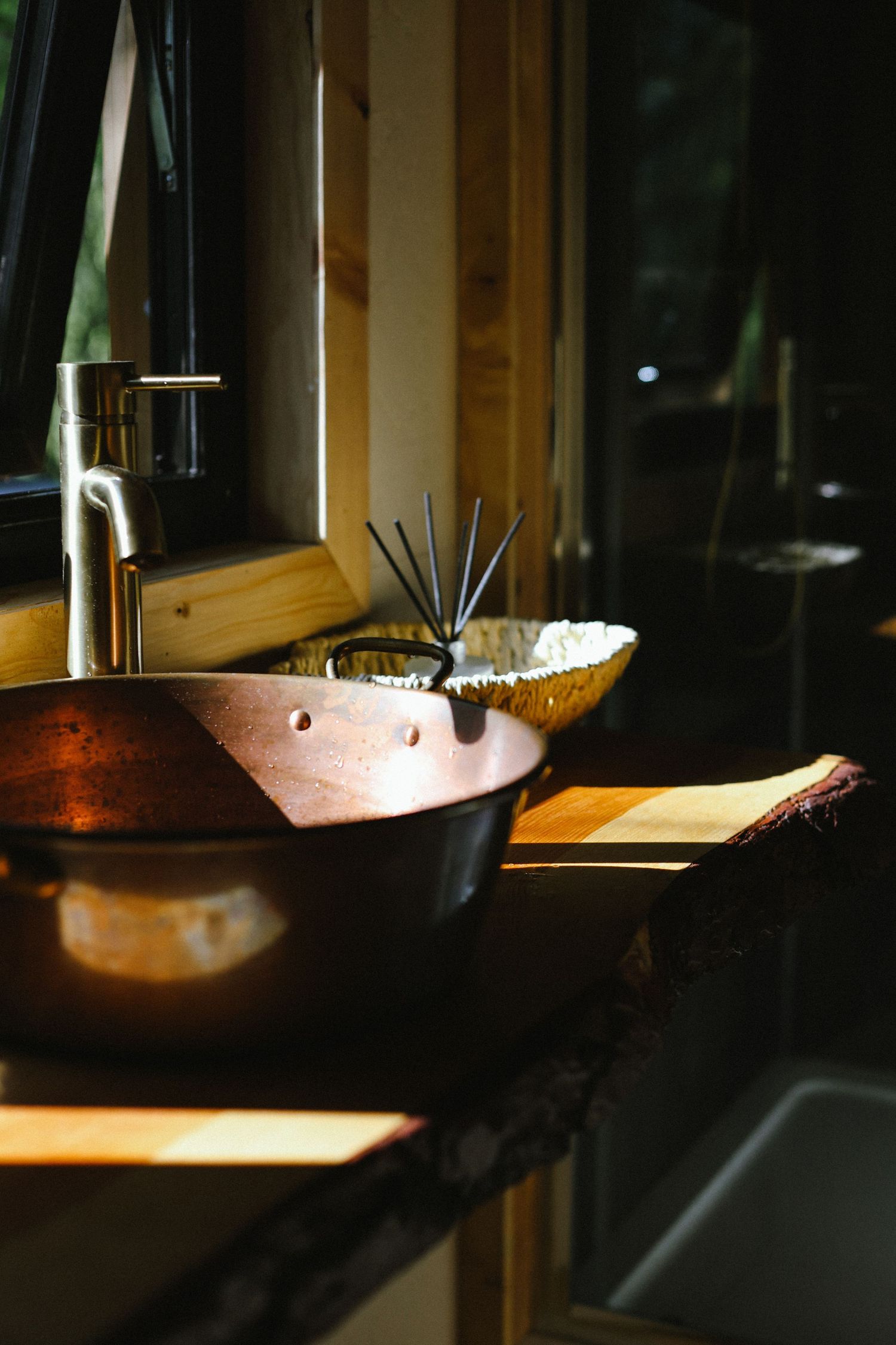 Montage of copper cooking pans with dramatic lighting casting moody shadows in a dark kitchen setting.