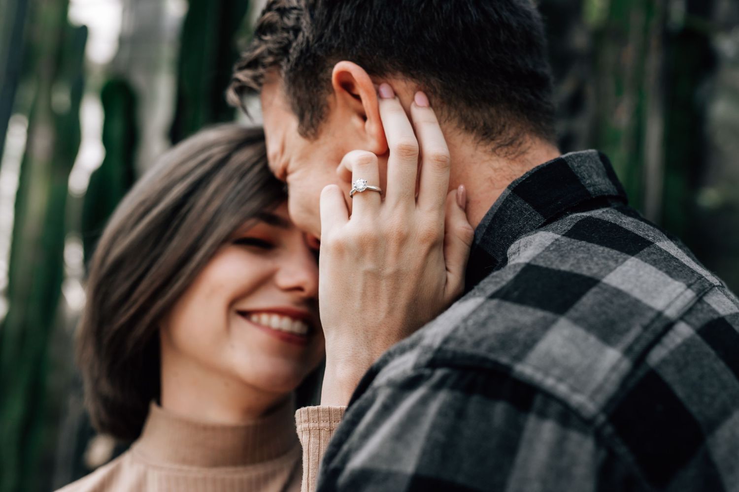 An intimate engagement photo showing a close-up moment with a diamond ring.