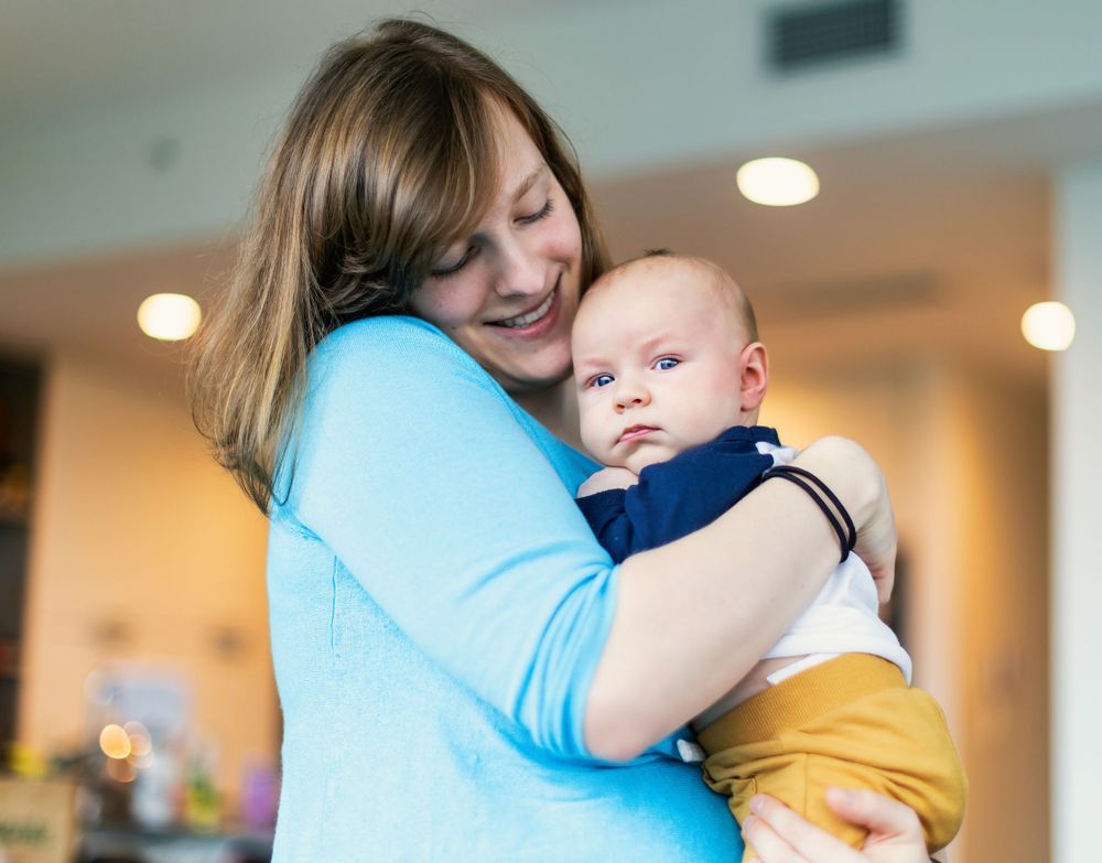 A tender moment as parent and baby embrace, with parent wearing light blue and baby in navy and yellow.