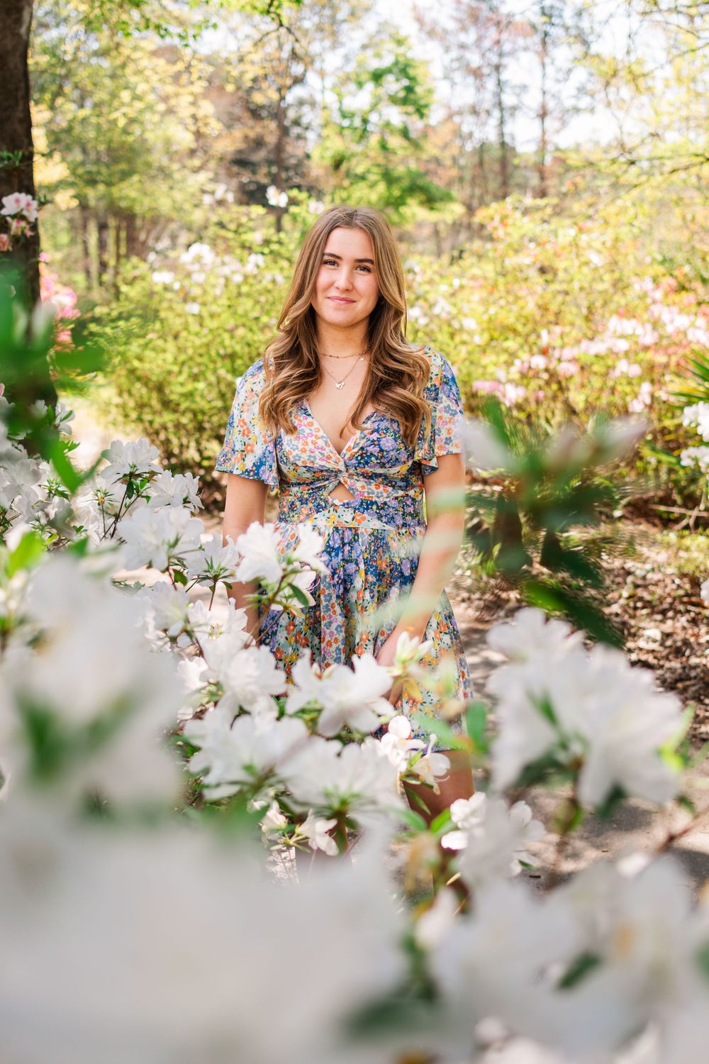 Floral dress portrait among blooming white flowers in a spring garden setting.