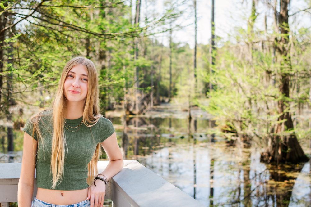 Casual spring fashion photography on a wooden deck overlooking a serene swamp landscape.