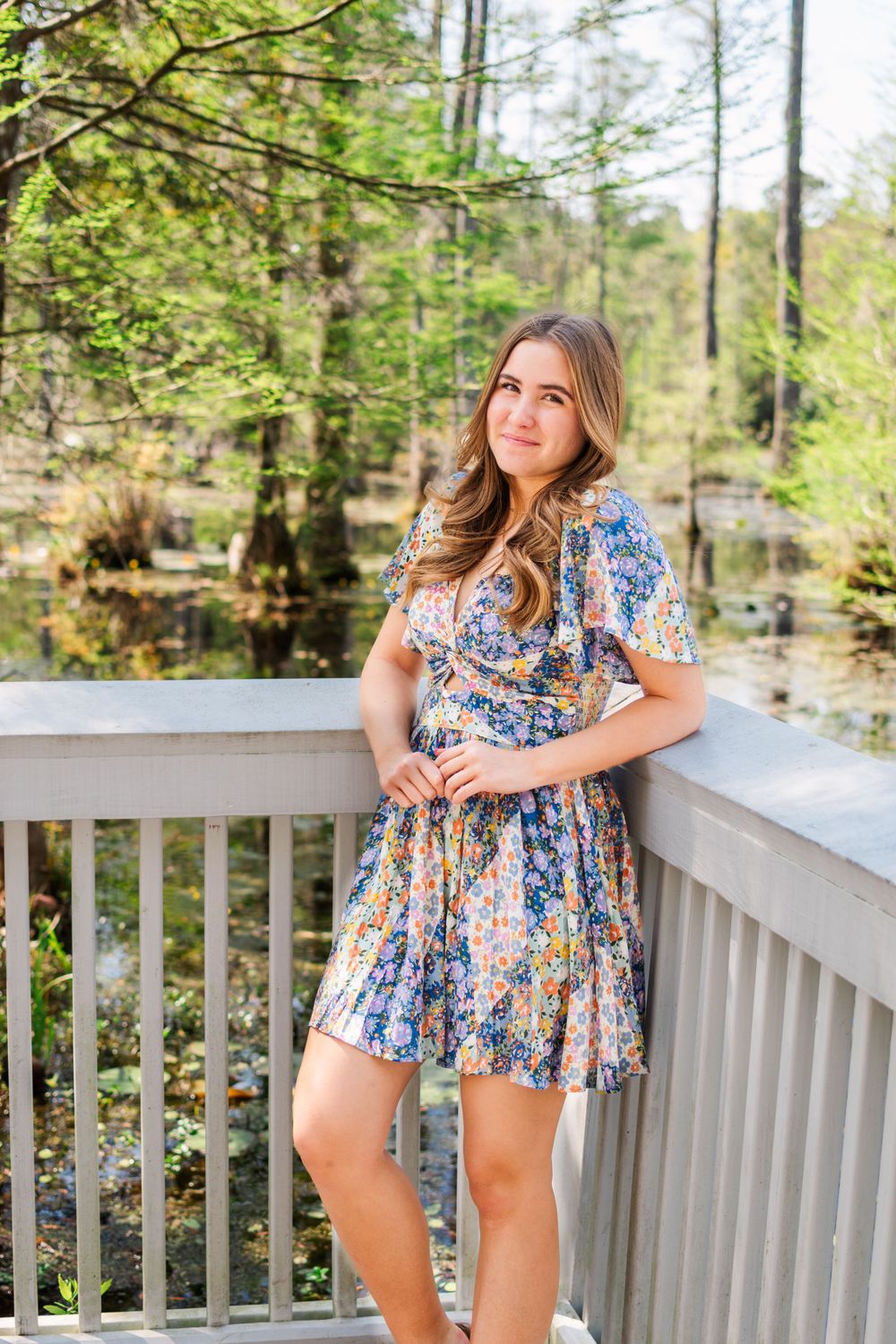 A floral spring dress outfit styled with a scenic woodland boardwalk and pond backdrop.