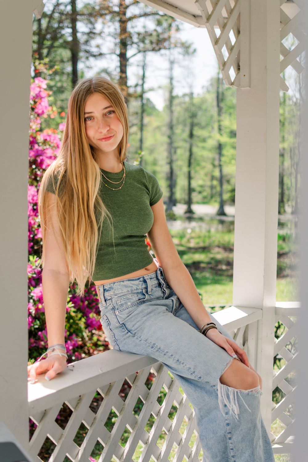 Portrait in a white gazebo surrounded by blooming pink azaleas and pine trees.
