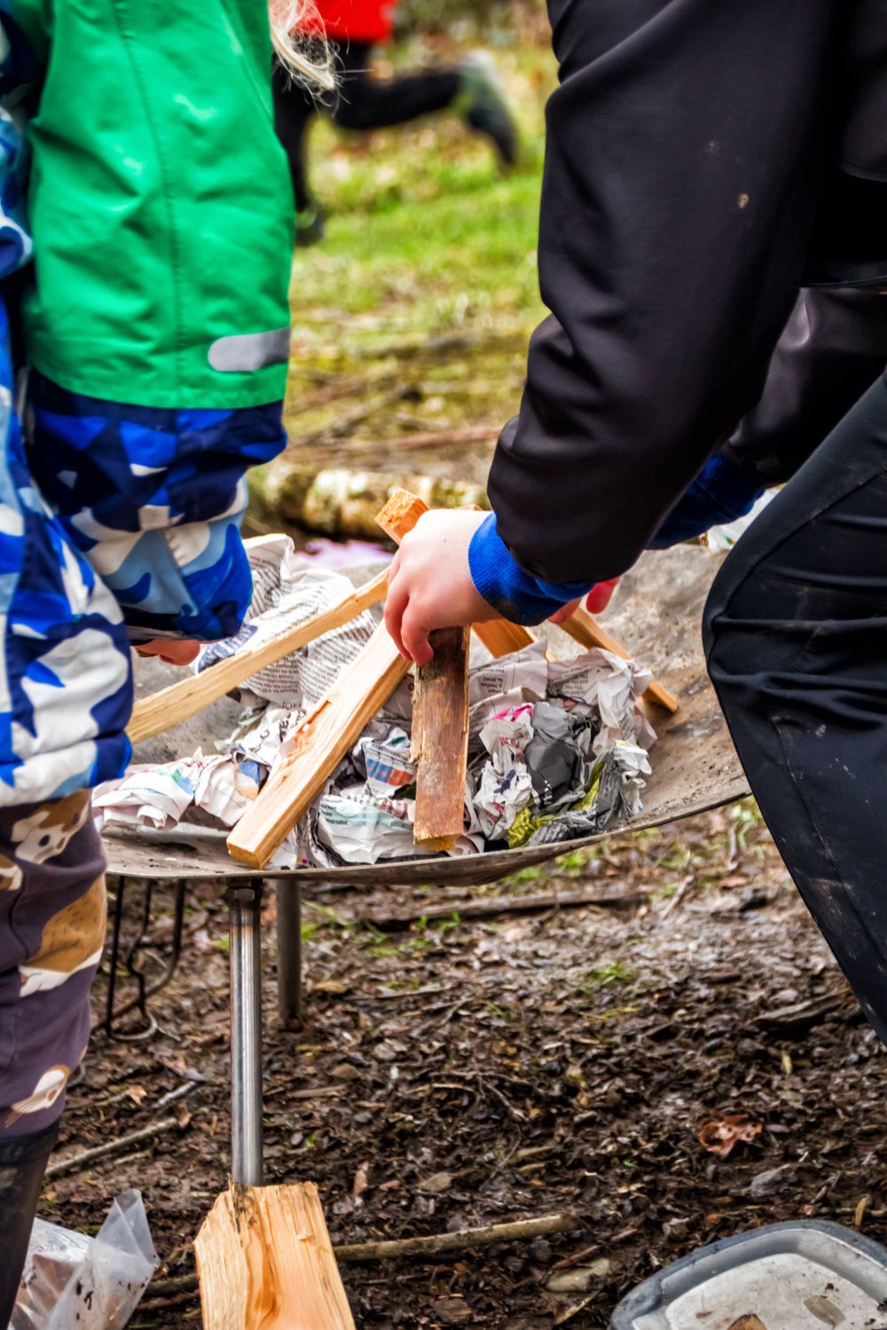 Hands preparing kindling and materials for outdoor fire making.