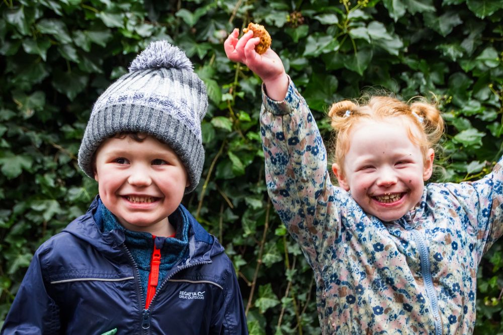 Two children in winter hats showing excitement outdoors.