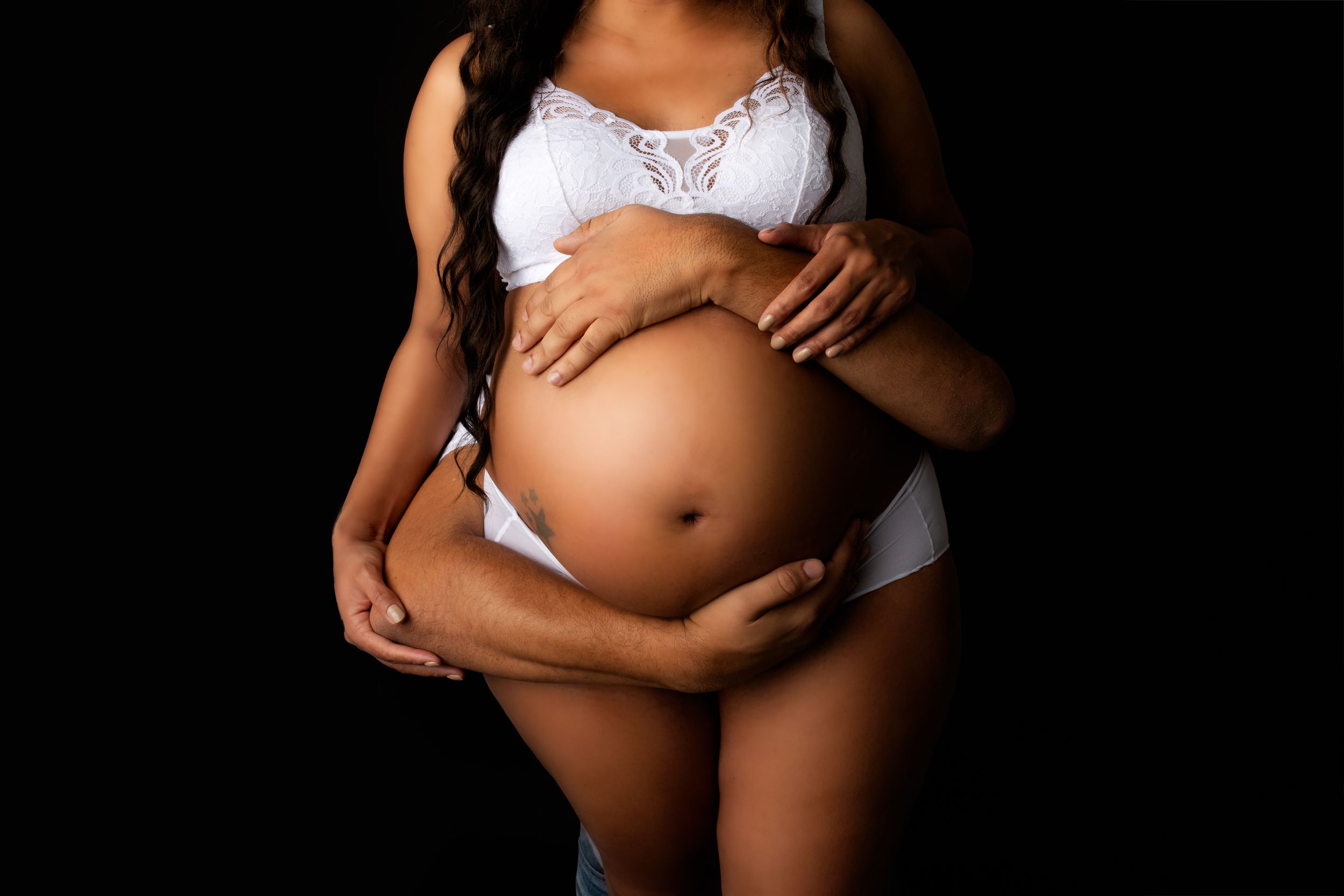 Studio Couple’s Maternity Portrait – Northern KY & OH – A dramatic black-background shot of expecting parents, hands gently on the baby bump