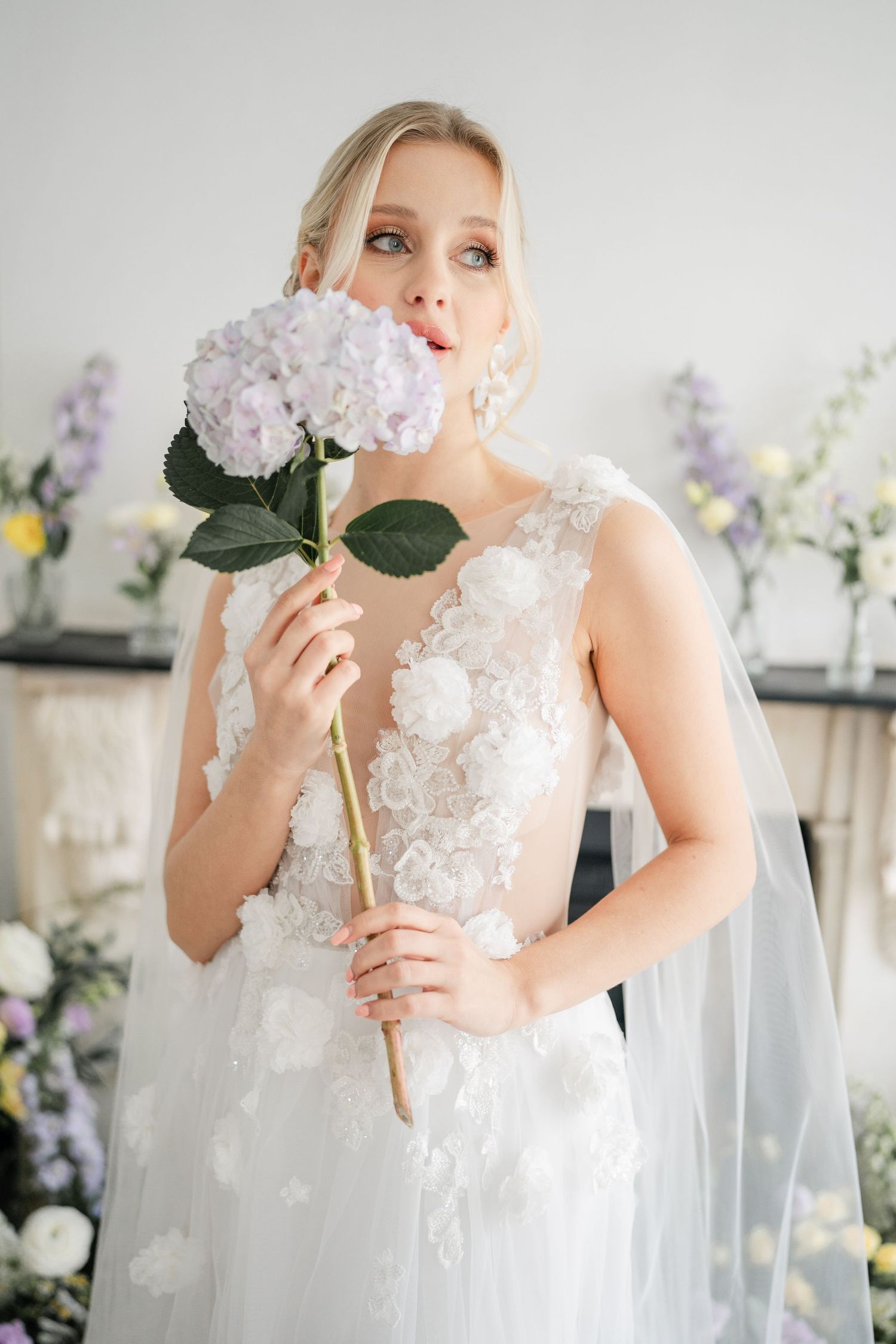 Romantic bridal portrait with soft pink hydrangeas against white backdrop.