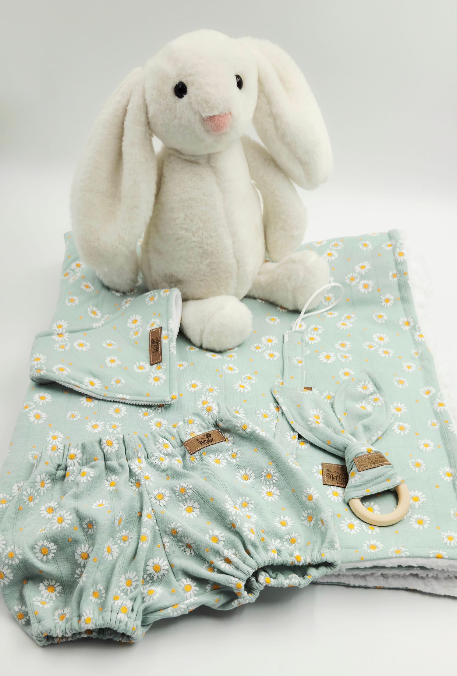 White plush bunny toy displayed on a light blue floral print baby blanket set.