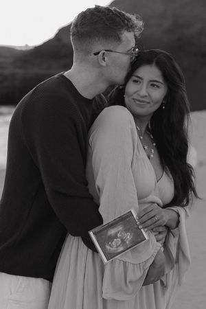 A romantic black and white photo series showing a couple embracing and sharing intimate moments on the beach.