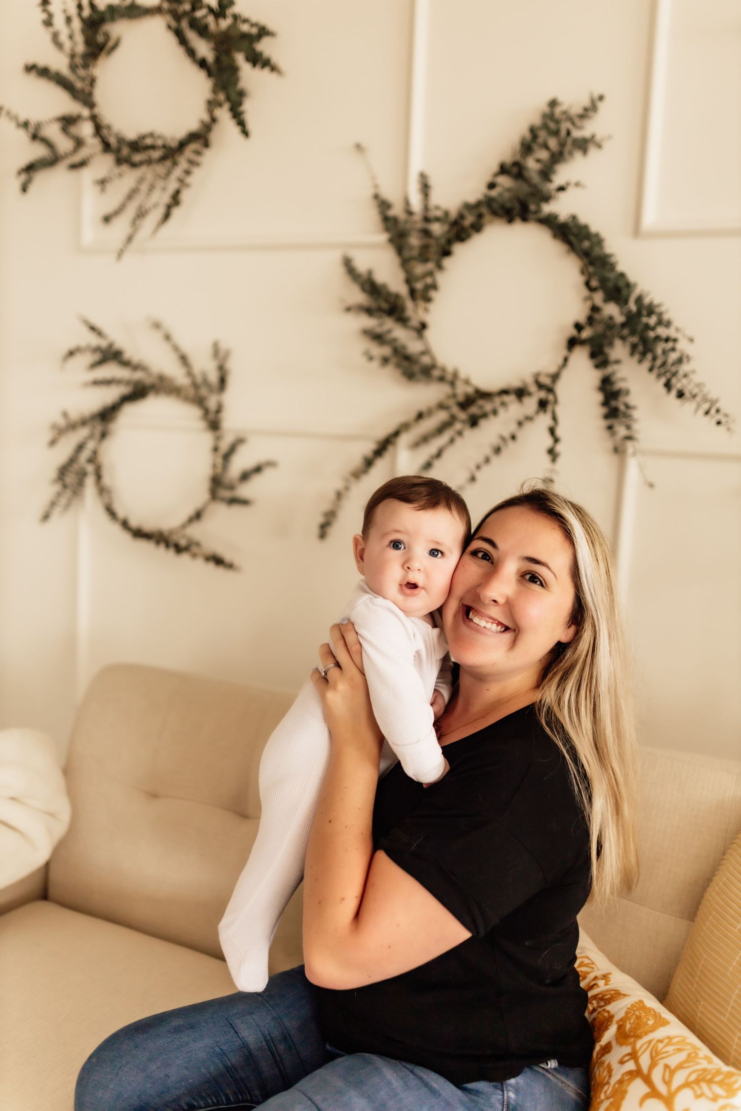 Mother and baby sharing joyful moments on a cozy beige couch.