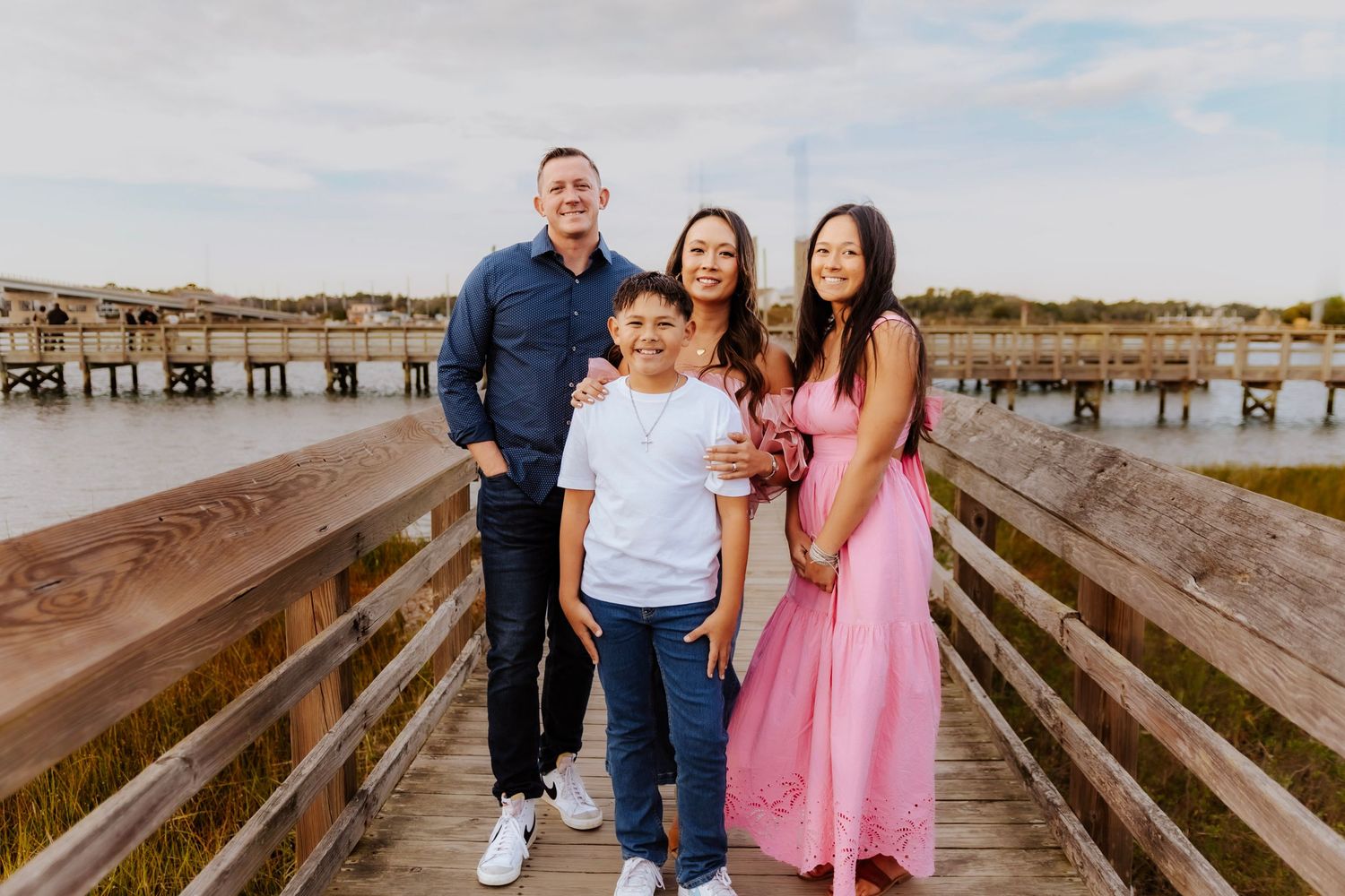 Family enjoying a sunset moment together on a wooden pier.