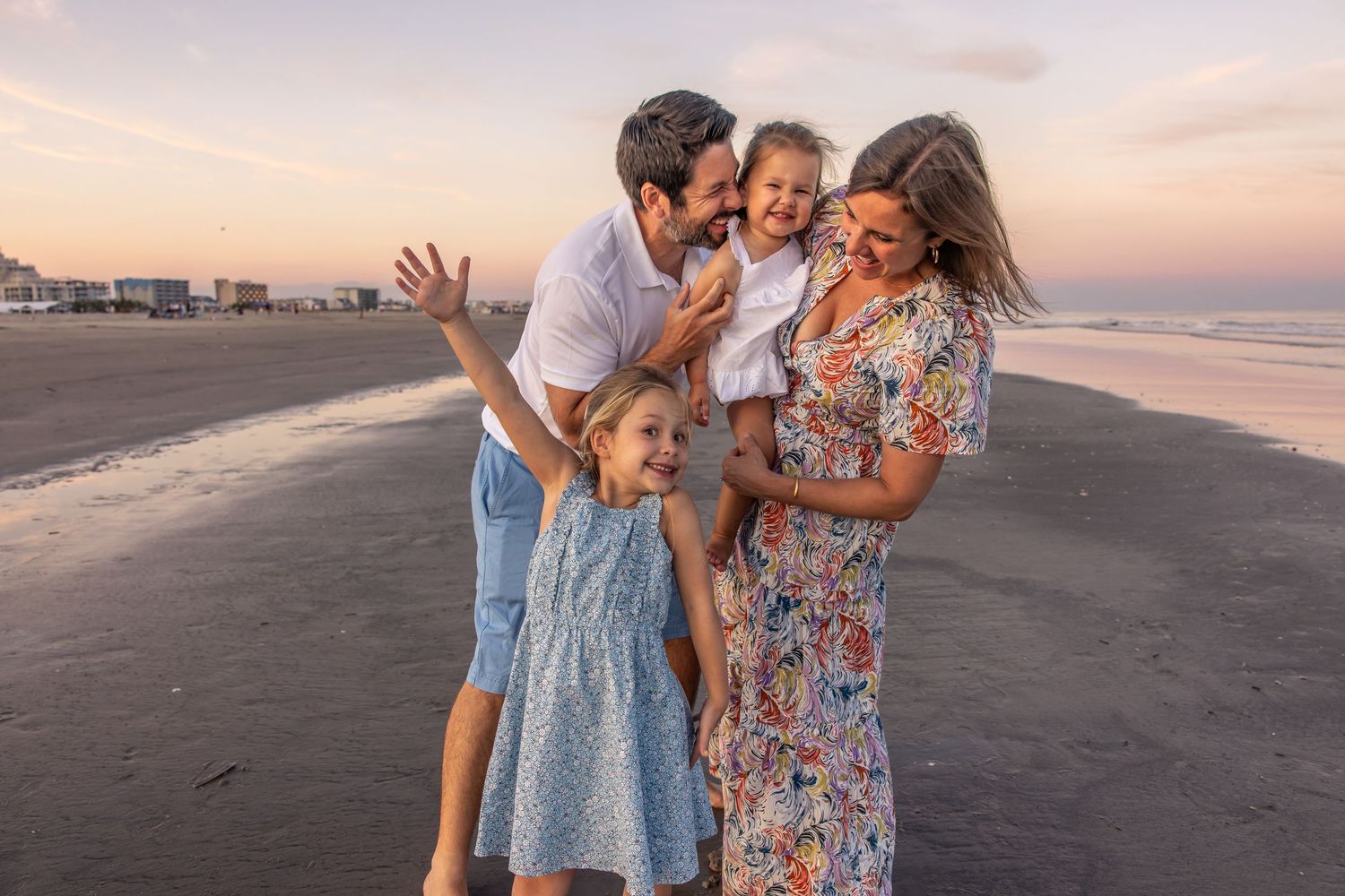 Joyful family moment captured during sunset on beach with ocean backdrop.