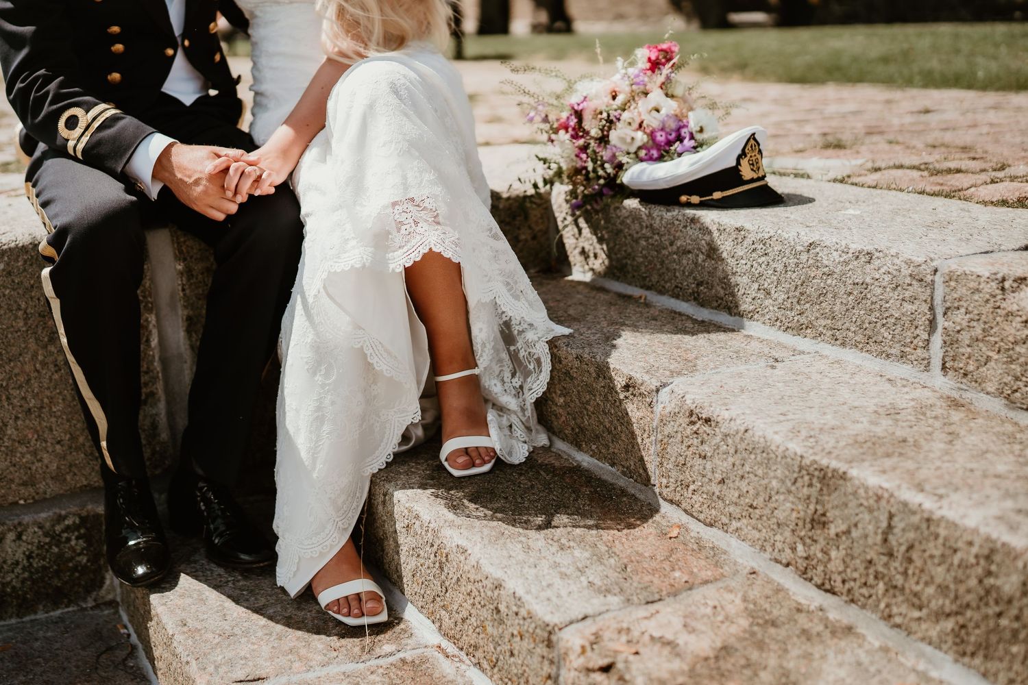 A close-up view of wedding attire and footwear on rustic stone steps with flowers nearby.