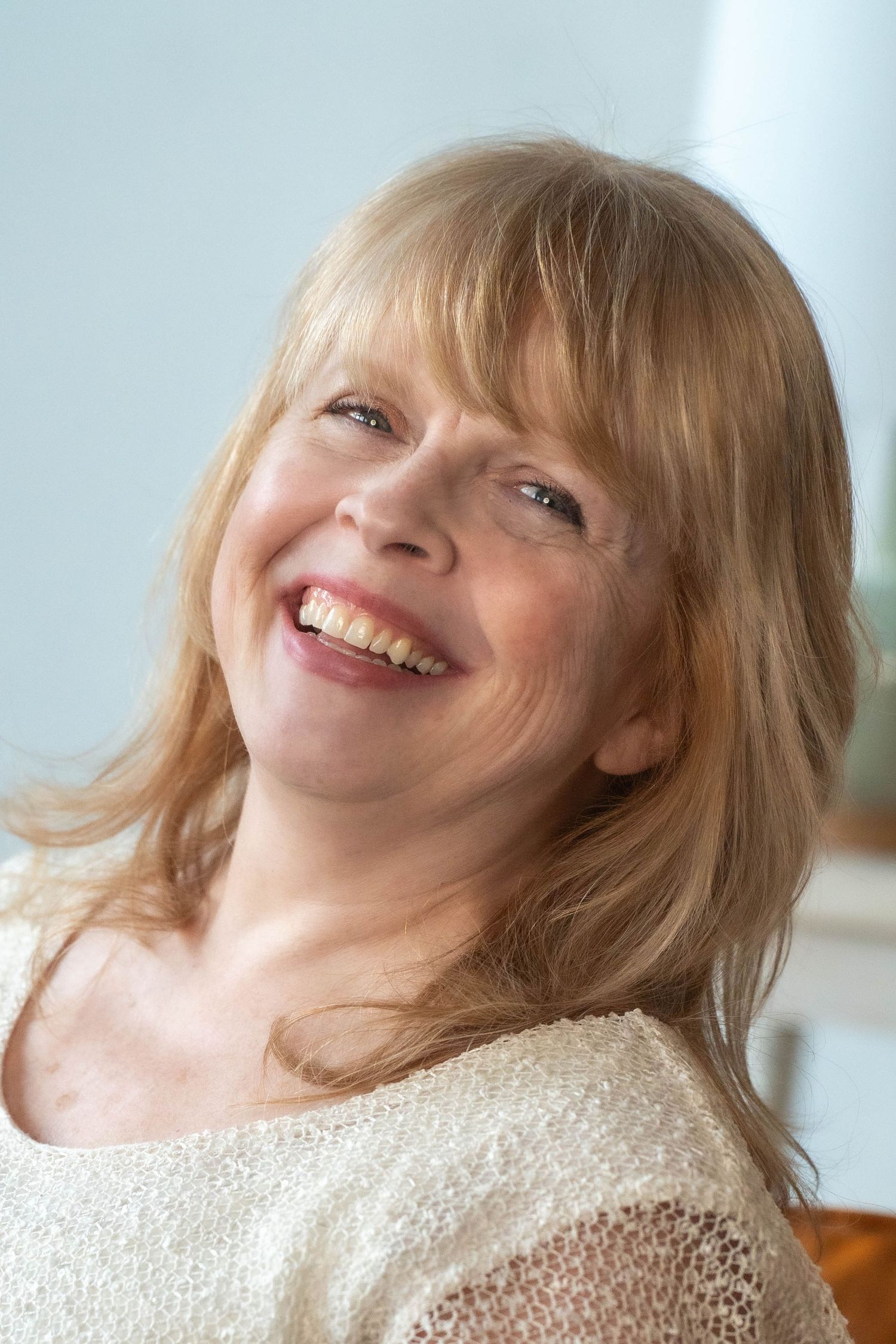 Series of joyful expressions in a cream colored sweater against light blue background.