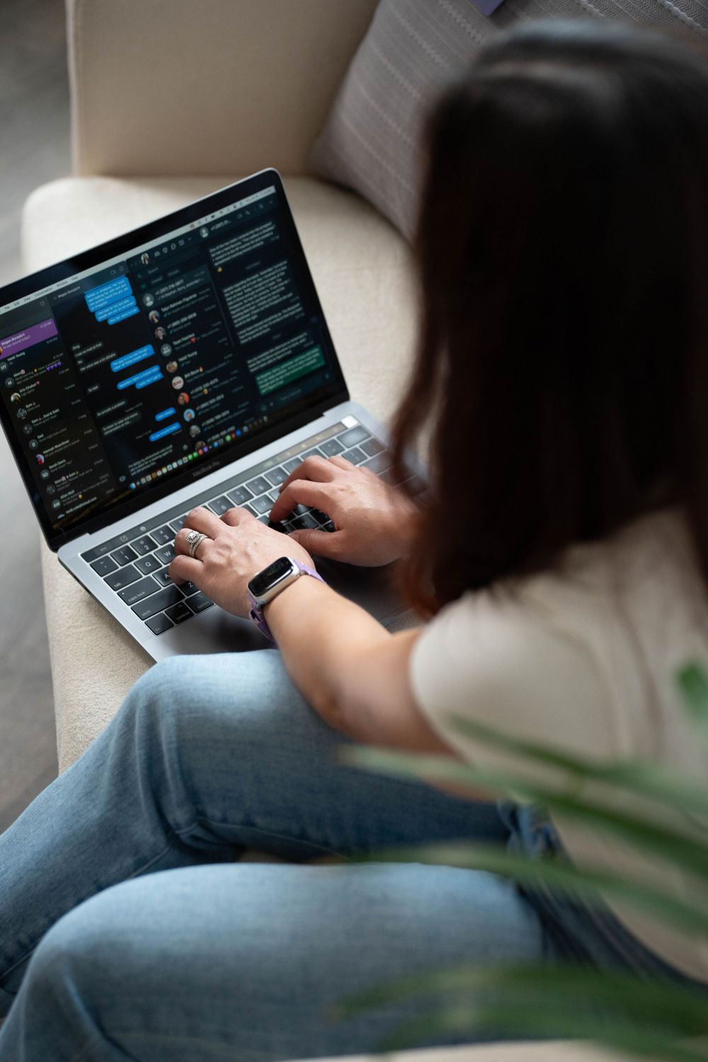 Person typing on MacBook laptop showing dark interface screen with data visualization.