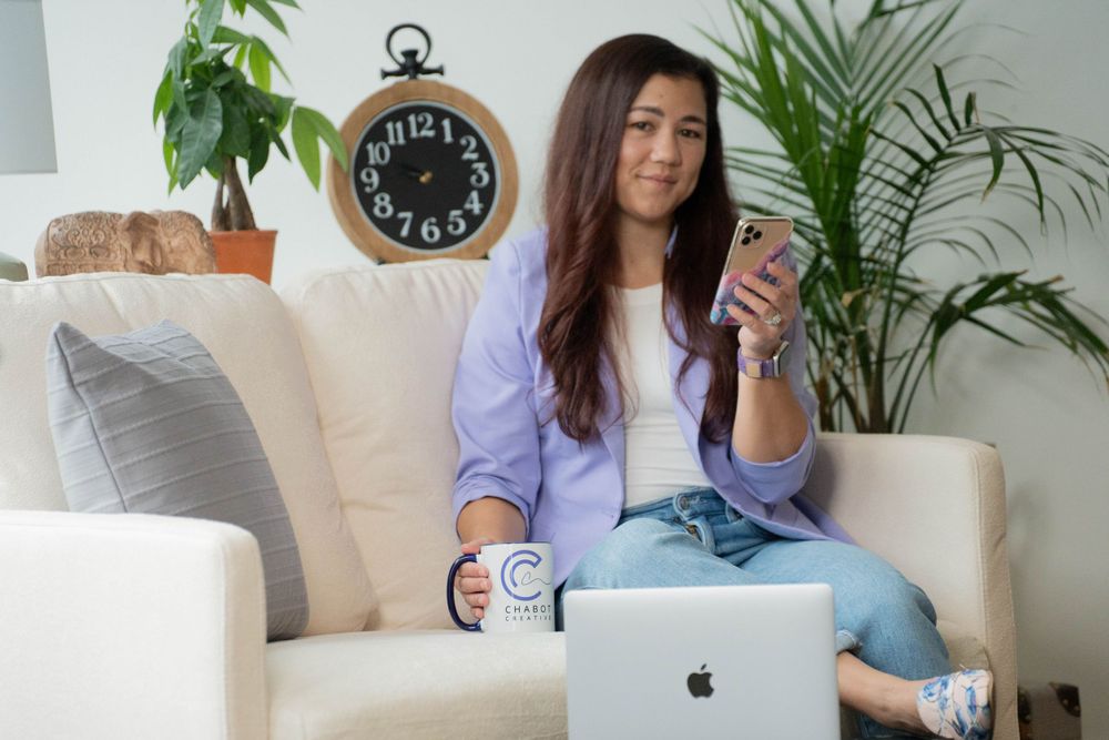 Professional working from home on laptop with phone and plants in cozy living room setting.