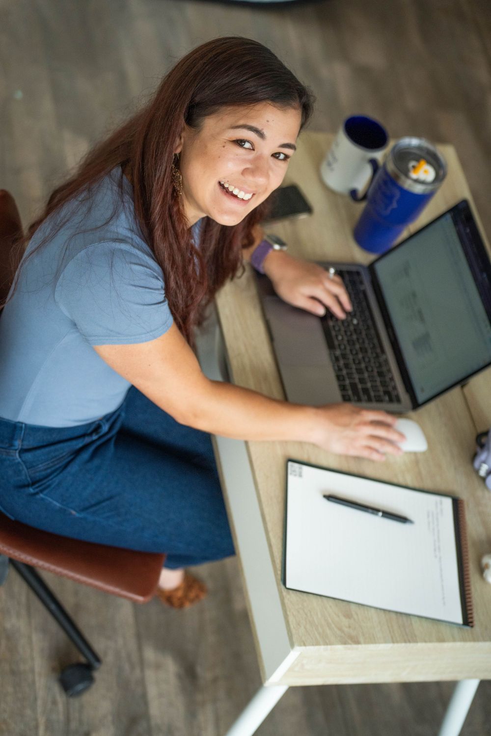 Overhead view of someone working at modern desk with laptop and notebook.