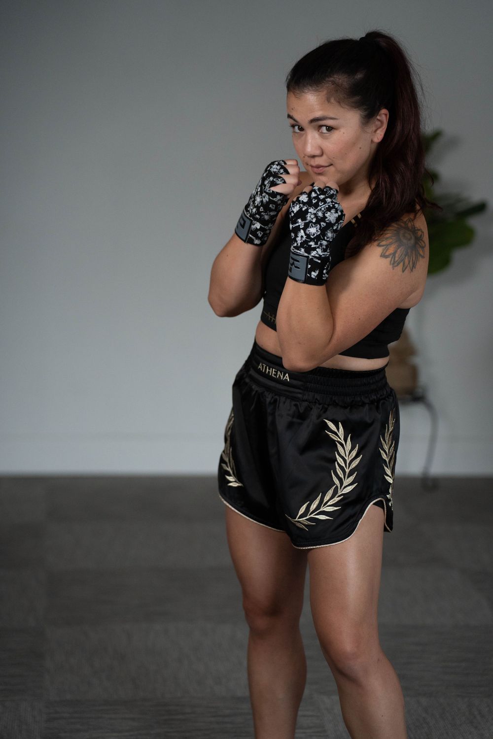 Athletic figure in boxing stance wearing patterned gloves and workout gear.