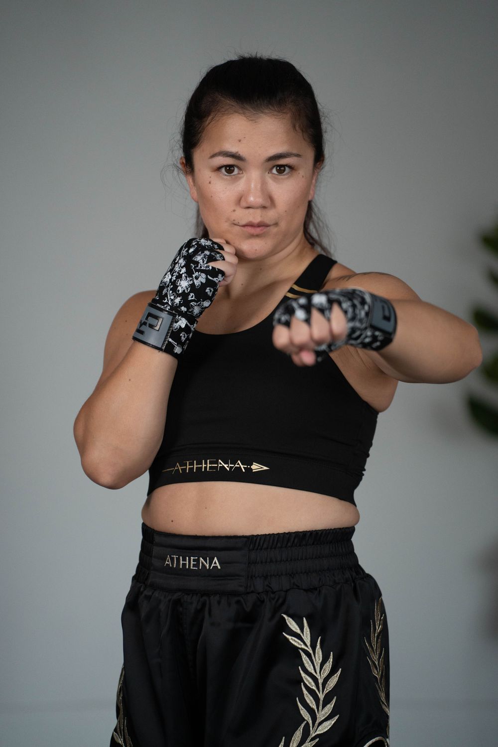 Boxer in fighting stance wearing Athena branded sports gear and patterned hand wraps.