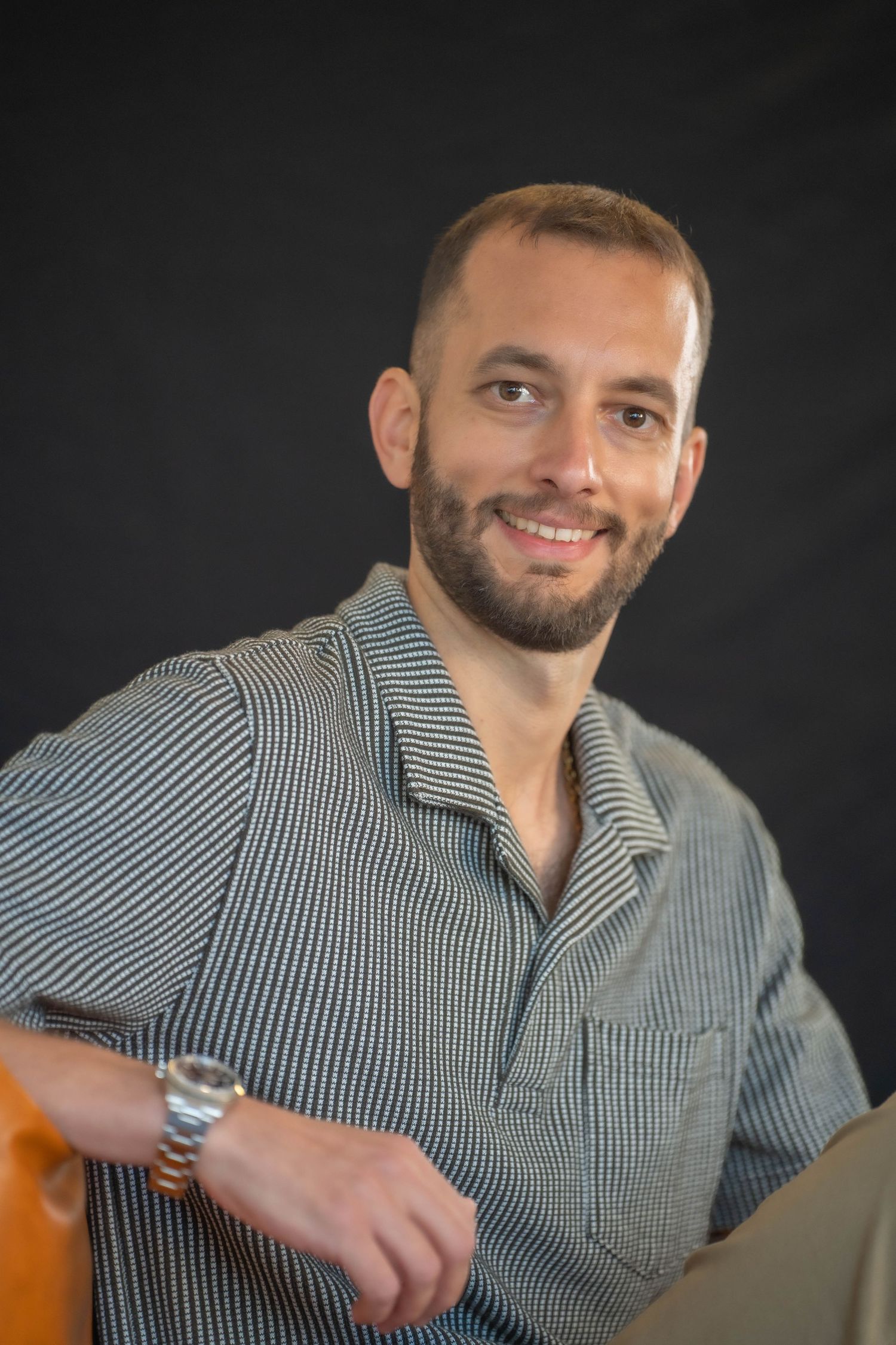 Casual portrait series in striped shirt against dark background.