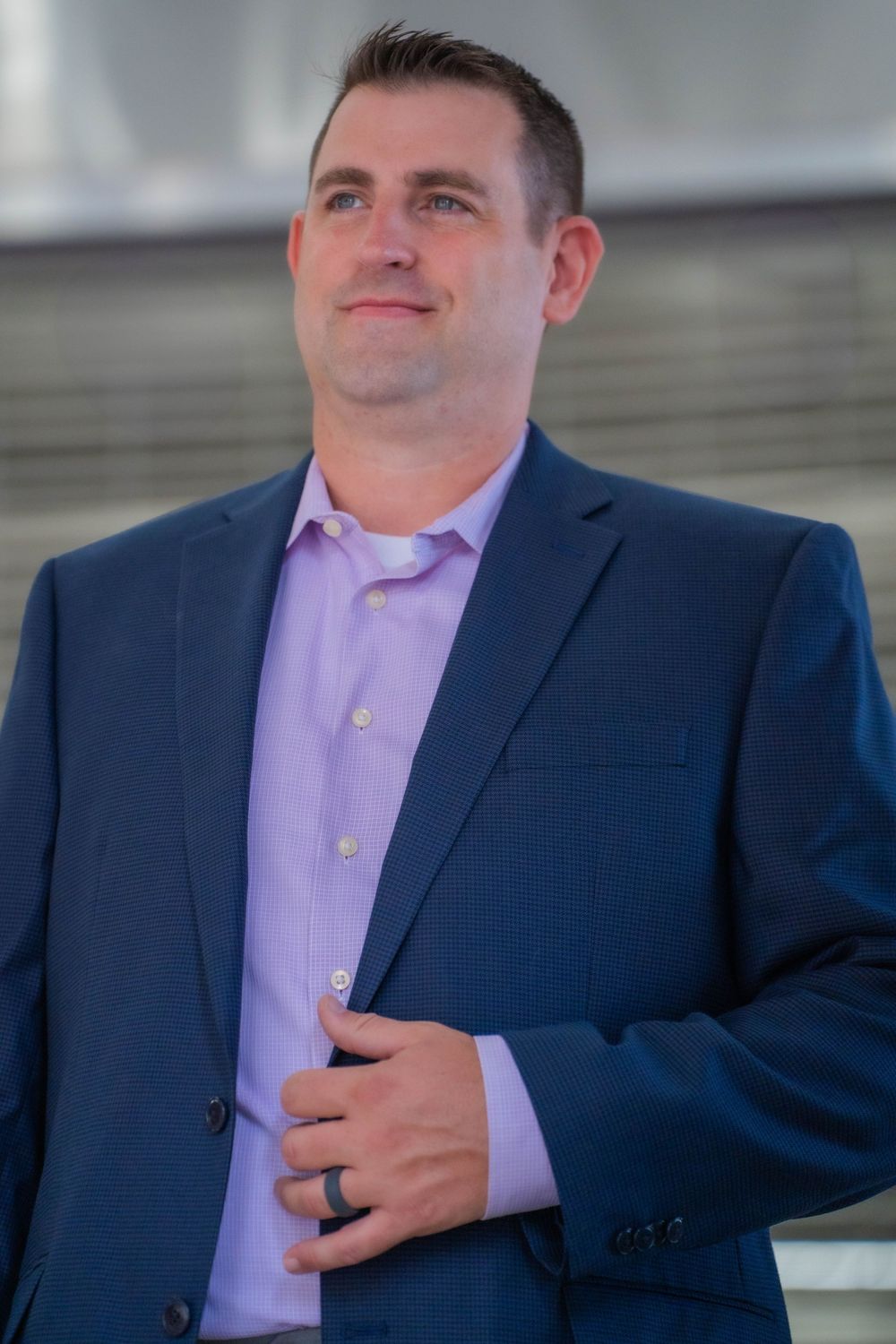 Professional headshots in navy suit and lavender shirt outdoors.