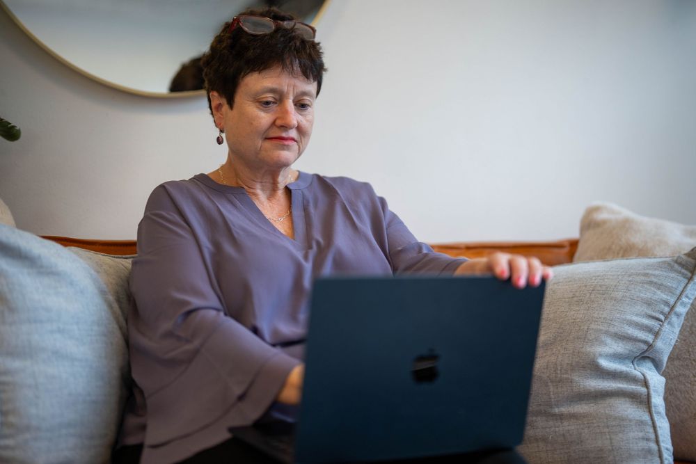 Person sitting on couch working on laptop in casual setting.