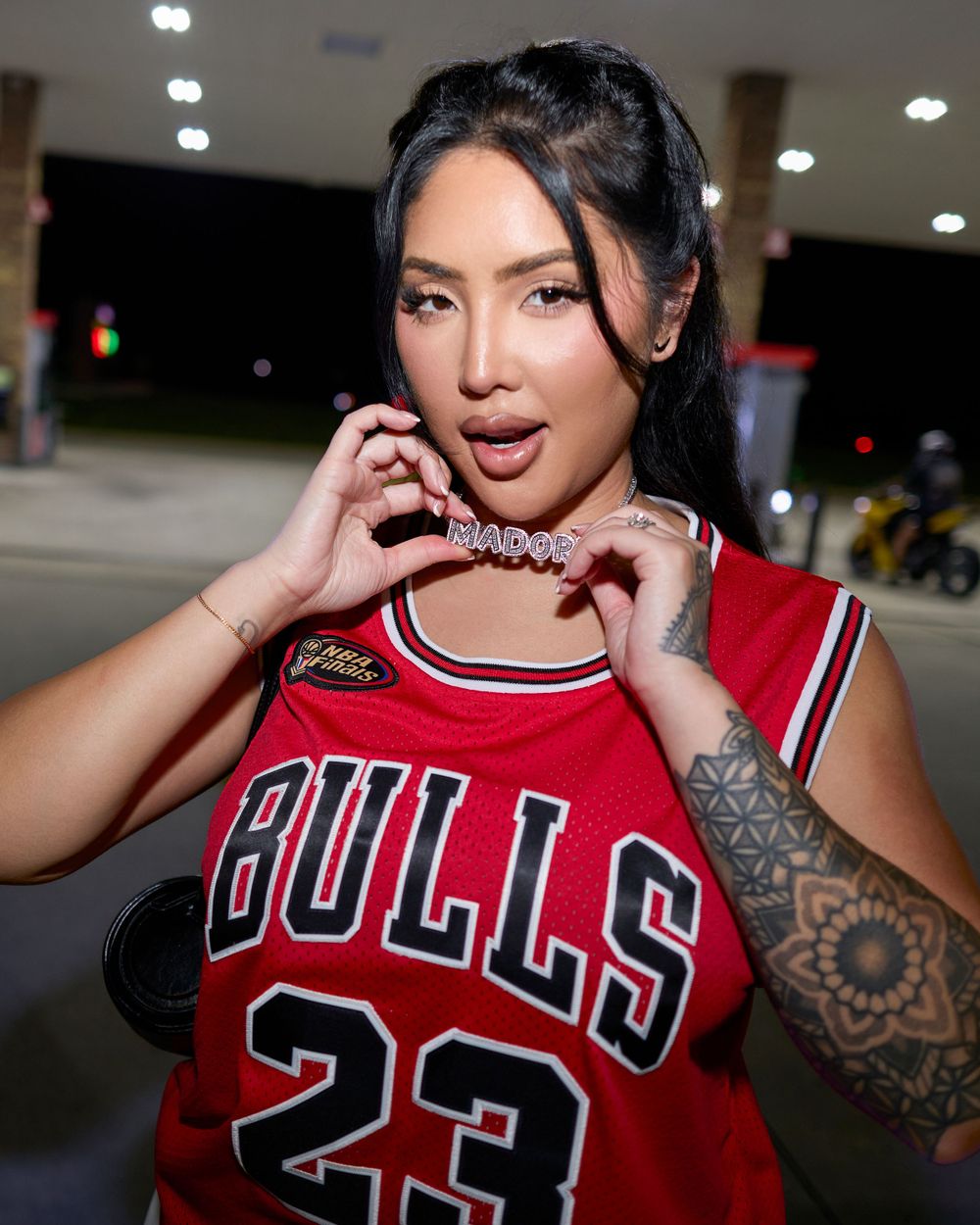 Person wearing Chicago Bulls red jersey with visible tattoos in indoor setting.
