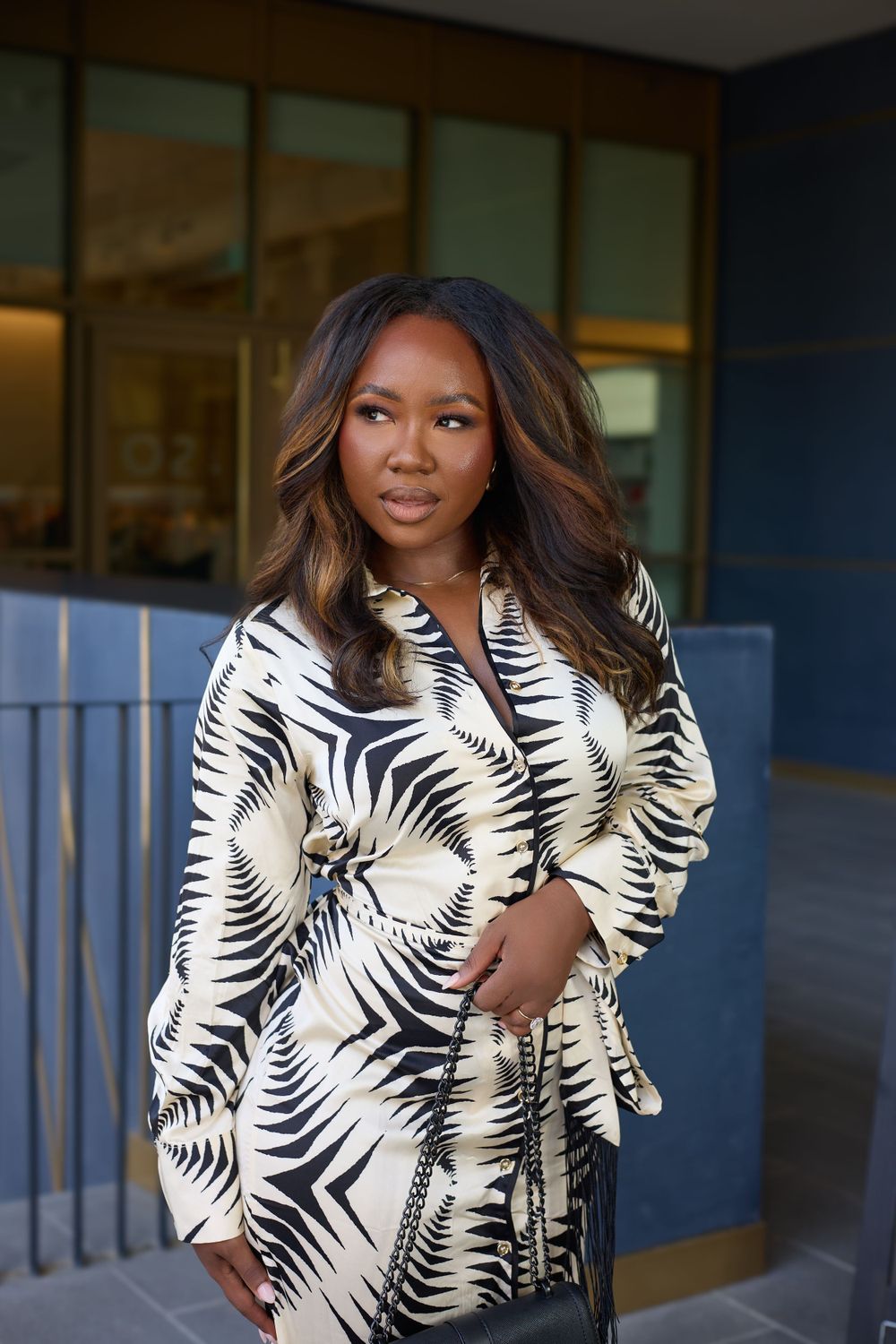 A woman models a black and white palm print jacket against a modern building exterior.