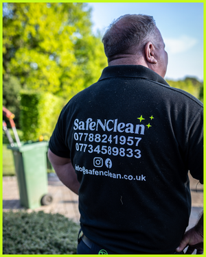 A worker wearing a SafeNClean company polo shirt with contact information displayed on the back.