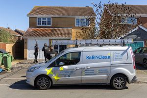 A Safe&Clean service van parked in front of a residential house with ladder racks on top and company branding visible.
