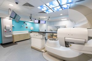 Modern medical treatment room with radiation therapy equipment and blue accent walls.