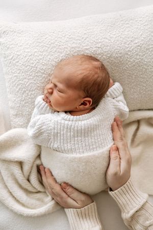 Natural newborn photography Nottingham baby sleeping in soft blanket with parents hands